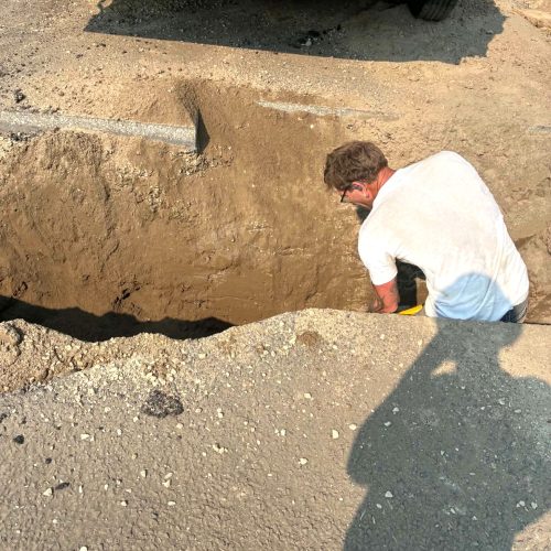 Plumber working in excavated trench during residential sewer line replacement