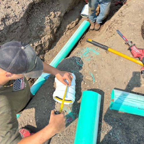 Plumbers measuring new sewer pipe and fittings before installation